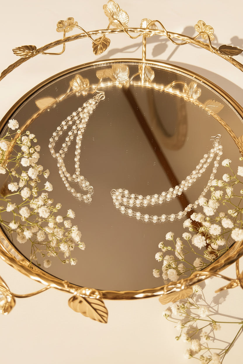 A pair of double-strand beaded jhumkha chain displayed on a decorative gold-toned mirror stand.